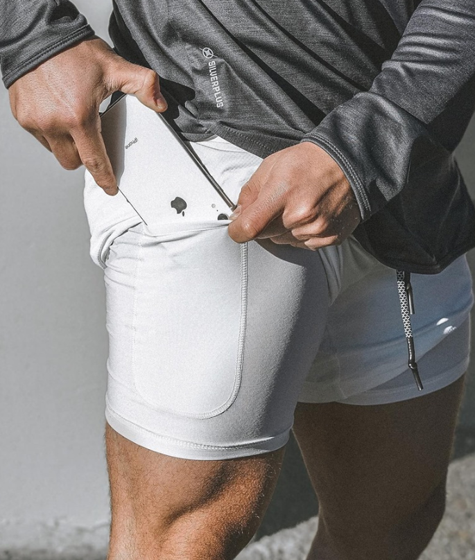 A man wearing white color ATHX DualSport Fitness Shorts a product from mensathletix the best Men athletic shorts Gym shorts Mens running shorts Crossfit shorts Sports shorts sports shorts for Men gym shorts